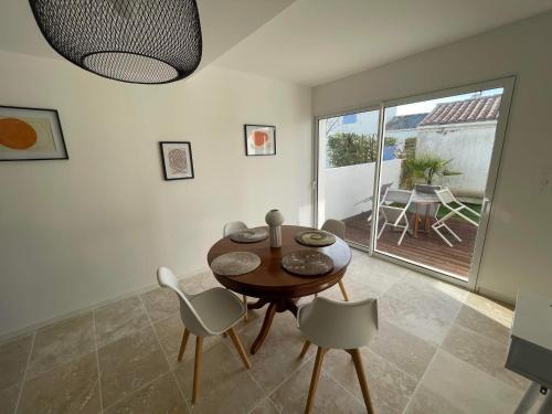 a dining room with a table and chairs and a patio at Charmante maison au coeur du village de Saint-Trojan-les-Bains in Saint-Trojan-les-Bains