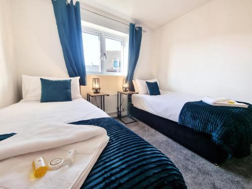 - 2 lits dans une chambre dotée de rideaux bleus dans l'établissement Stylish 3 Bedrooms & 2 Bathrooms House, Free Parking!, à Cambridge