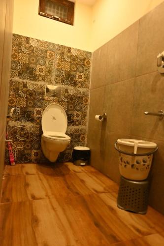 a bathroom with a toilet and a wooden floor at The Bunker House in Chopta