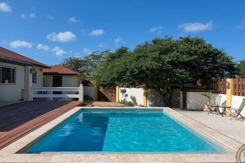 een zwembad in een achtertuin met een houten terras bij Private Peaceful Paradise on One Happy Island in Oranjestad