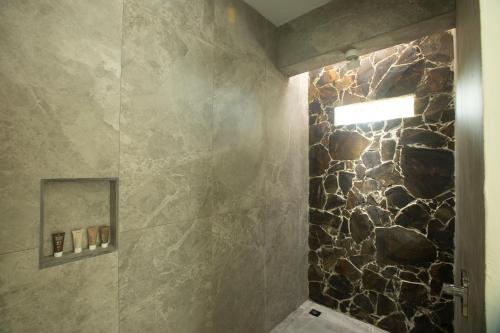 a bathroom with a shower with a stone wall at Adeluna Luxury Villas in Montezuma