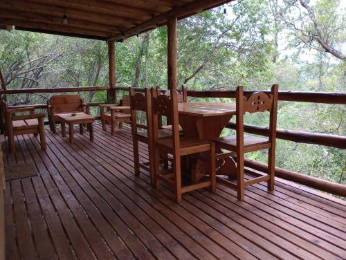 un porche de madera con mesa y sillas. en Cabaña La Isla II en 