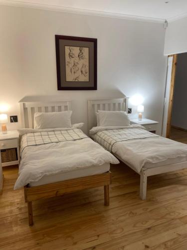 two beds in a room with white walls and wooden floors at Swakopmund private room in family home in Swakopmund