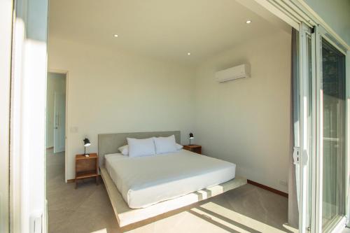 a white bedroom with a bed and a window at Adeluna Luxury Villas in Montezuma