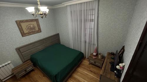 Un dormitorio con una cama verde y una mesa en Apartment Urushadze, en Batumi