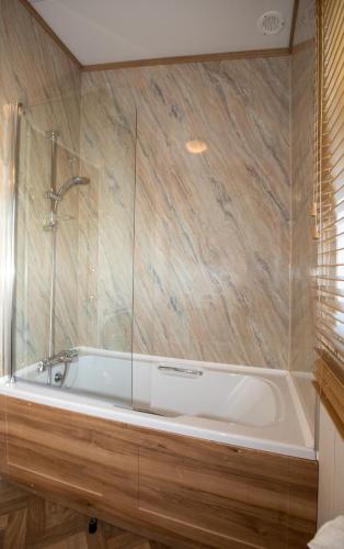 a bathroom with a bath tub with a shower at Stewarts Resort Lodge 27 in St. Andrews