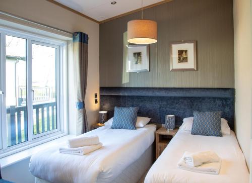 two beds in a room with a window at Stewarts Resort Lodge 27 in St. Andrews