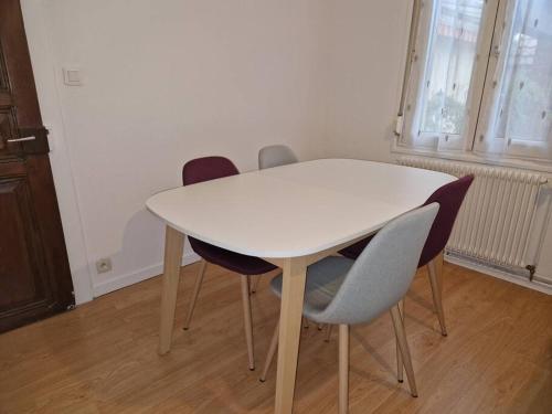 - une table et des chaises blanches dans la chambre dans l'établissement Appartement Le Grillenbreit, à Colmar