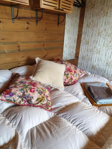 a bed with pillows on it in a room at Le Chalet du Clos Giot in Saint-Vaast-la-Hougue
