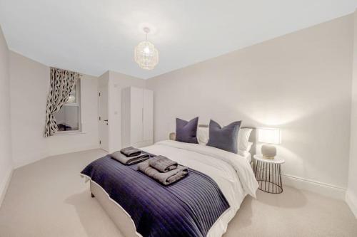 a white bedroom with a large bed with purple pillows at Trendy 2 bedroom 2 bathroom apartment minutes from seafront in St Leonard's Hastings in St. Leonards