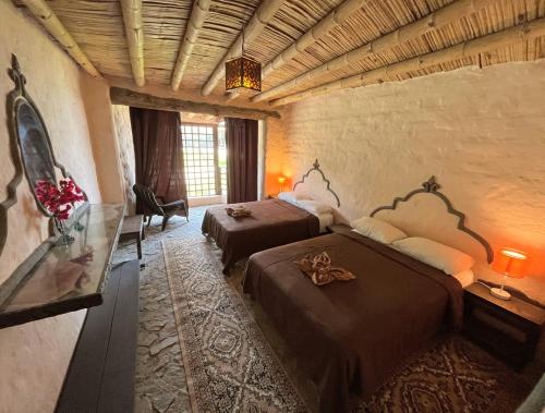 a bedroom with two beds and a glass table at Darenas Hacienda in Aucallama