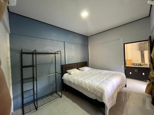 - une chambre avec un lit et un mur bleu dans l'établissement Cabina Don Luis, à San Juanillo