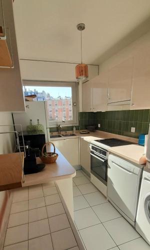 une cuisine avec des appareils blancs et une grande fenêtre dans l'établissement Chez Sophie, à Paris