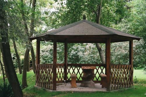 a wooden gazebo with a tree in the grass at Villa Hedi in Dunakiliti