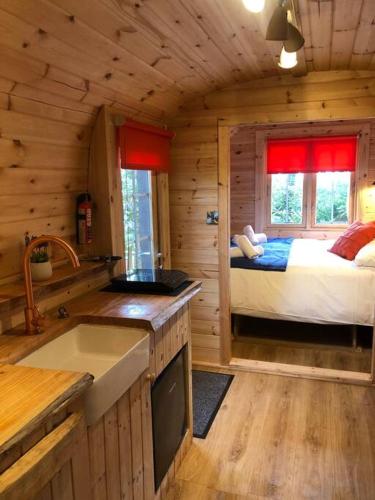 a kitchen with a bed in a log cabin at Waterside Cader Cabin with Hot Tub in Barmouth