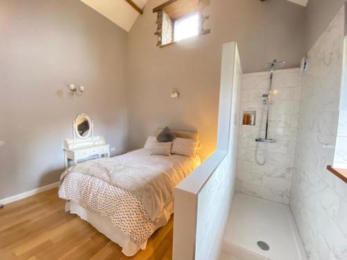 ein Schlafzimmer mit einem Bett und einer ebenerdigen Dusche in der Unterkunft Heronston Barn Cottage in Bridgend