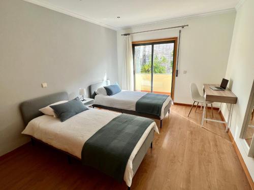 two beds in a room with a desk and a laptop at Villa Florence in Mogege