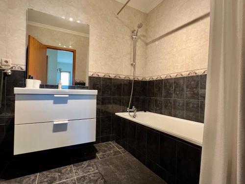 ein Badezimmer mit einer Badewanne, einem Waschbecken und einem Spiegel in der Unterkunft Villa Florence in Mogege