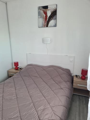 a bed in a room with two night stands and a picture at Appartement avec vue sur le lac in Vieux-Boucau-les-Bains