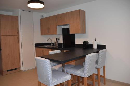 kuchnia z czarnym stołem i białymi krzesłami w obiekcie Le Saint Pierre en Baie Appt 3-4 pers parking privé w mieście Saint-Valéry-sur-Somme