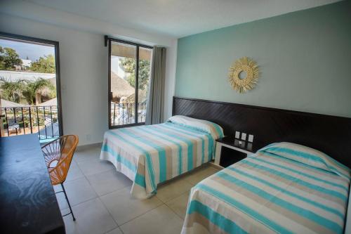 a hotel room with two beds and a balcony at Hotel Camino Del Sol in Puerto Escondido