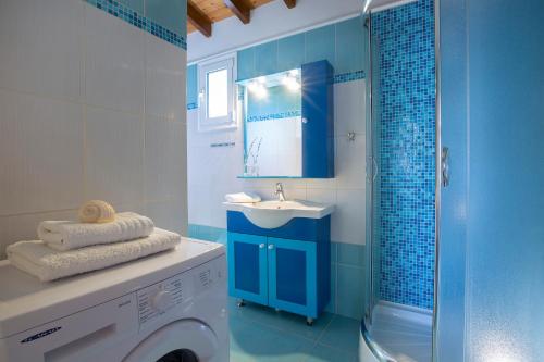 a blue bathroom with a sink and a washing machine at AmElia Villa in Spanokhórion