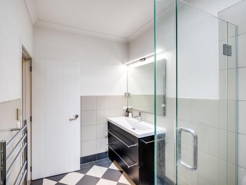 a bathroom with a sink and a glass shower at Busby Hill Villa - Havelock North Holiday Home in Havelock North