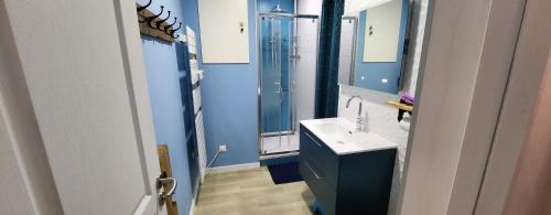 une salle de bain bleue avec un lavabo et un miroir dans l'établissement La Perle du Sancy, à La Bourboule