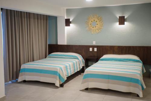 two beds in a hotel room with a mirror at Hotel Camino Del Sol in Puerto Escondido
