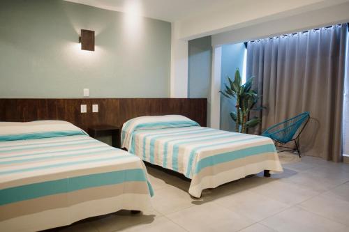 a hotel room with two beds and a window at Hotel Camino Del Sol in Puerto Escondido