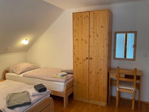 a bedroom with two beds and a wooden cabinet at TURISTIČNA KMETIJA STREVC in Solčava