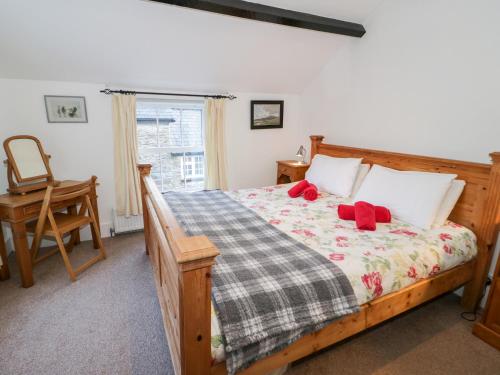 Schlafzimmer mit einem Holzbett mit roten Kissen in der Unterkunft Arwel in Capel Garmon