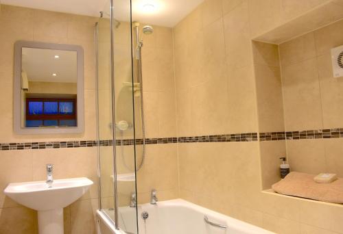 a bathroom with a shower and a sink and a tub at Corrie Apartment in Appin