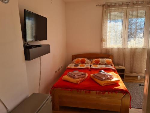 a bedroom with a bed with red sheets and a flat screen tv at Bisa in Soko Banja