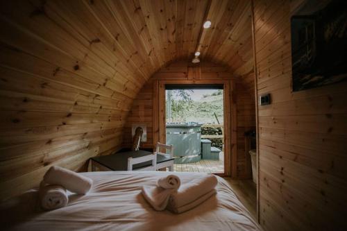 a log cabin bedroom with a bed and a window at Ash WINTER RETREAT- Hot tub & Log Bruner in Barmouth