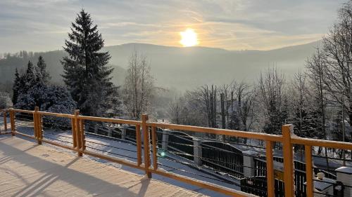a view of a snowy mountain with the sun in the background at Dwupoziomowe Apartamenty Leszczyna in Ustroń