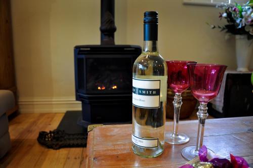 a bottle of wine sitting on a table with two glasses at Athelney Cottage Bed and Breakfast in Adelaide