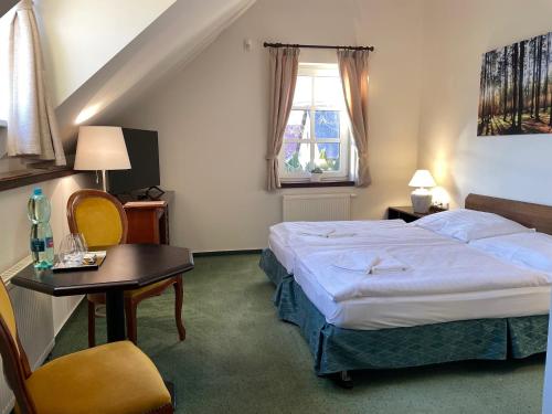 une chambre d'hôtel avec un lit, une table et une fenêtre dans l'établissement Bechnerův statek, à Lány