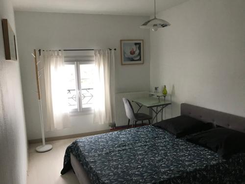 1 dormitorio con cama, mesa y ventana en Foix cœur de ville, en Foix