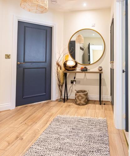 a hallway with a blue door and a mirror at Chic, immaculate Warwick apartment sleeps 4 & free private parking, easy walk to Warwick, castle, canal-side pub on doorstep - perfect for relaxing breaks, the races or workcation in Warwick