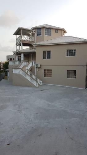 a large white building with a staircase in a parking lot at Kaibus Place- Quaint Quiet and Cosy in Morne Rouge