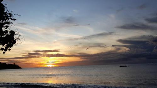 a sunset over the ocean with a boat in the water at Kaibus Place- Quaint Quiet and Cosy in Morne Rouge
