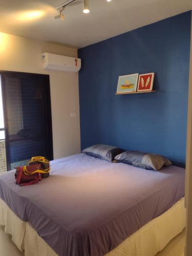 a blue bedroom with a bed with a backpack on it at Edifício Monte Carmel in Guarujá