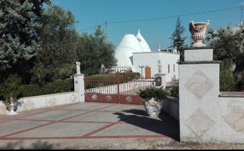 a house with a gate and a building with a dome at Trullo Nonna Rosa in Antonelli