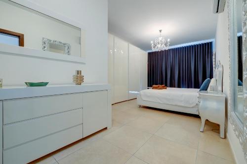 a white bedroom with a bed and a desk at Seafront Apartment Sliema in Sliema