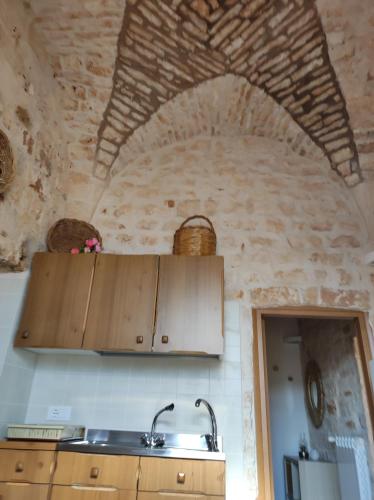 a kitchen with wooden cabinets and a stone wall at Trullo Nonna Rosa in Antonelli