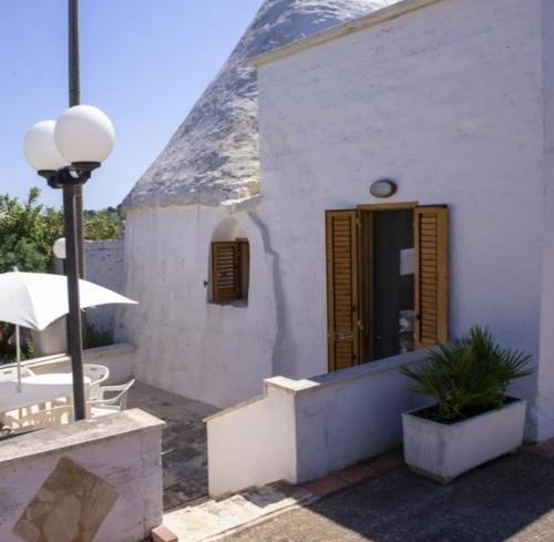 a white building with a wooden door and a table at Trullo Nonna Rosa in Antonelli