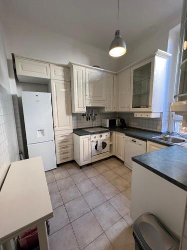 une cuisine avec des armoires blanches et un réfrigérateur blanc dans l'établissement Frontiere de Monaco 3 Pieces Vue Mer, à Cap d'Ail