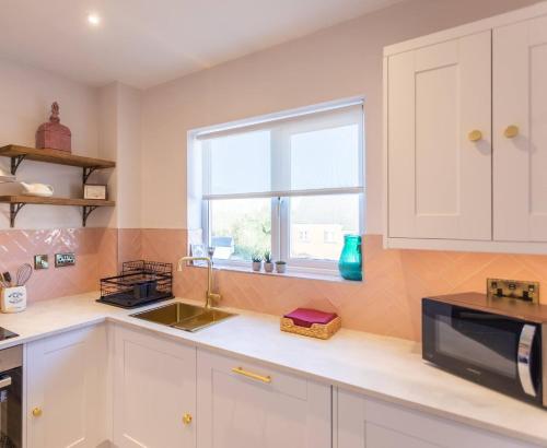 a kitchen with white cabinets and a sink and a window at Chic, immaculate Warwick apartment sleeps 4 & free private parking, easy walk to Warwick, castle, canal-side pub on doorstep - perfect for relaxing breaks, the races or workcation in Warwick