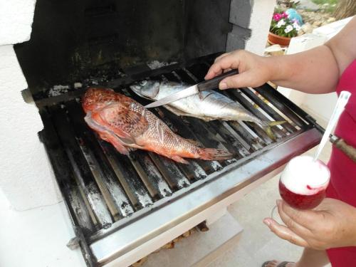 una persona está cocinando pescado en una parrilla en Adriatic Arteon, en Baška